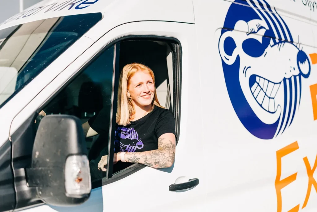 Hymyilevä RAT Express-kuljettaja istumassa pakettiautossa.