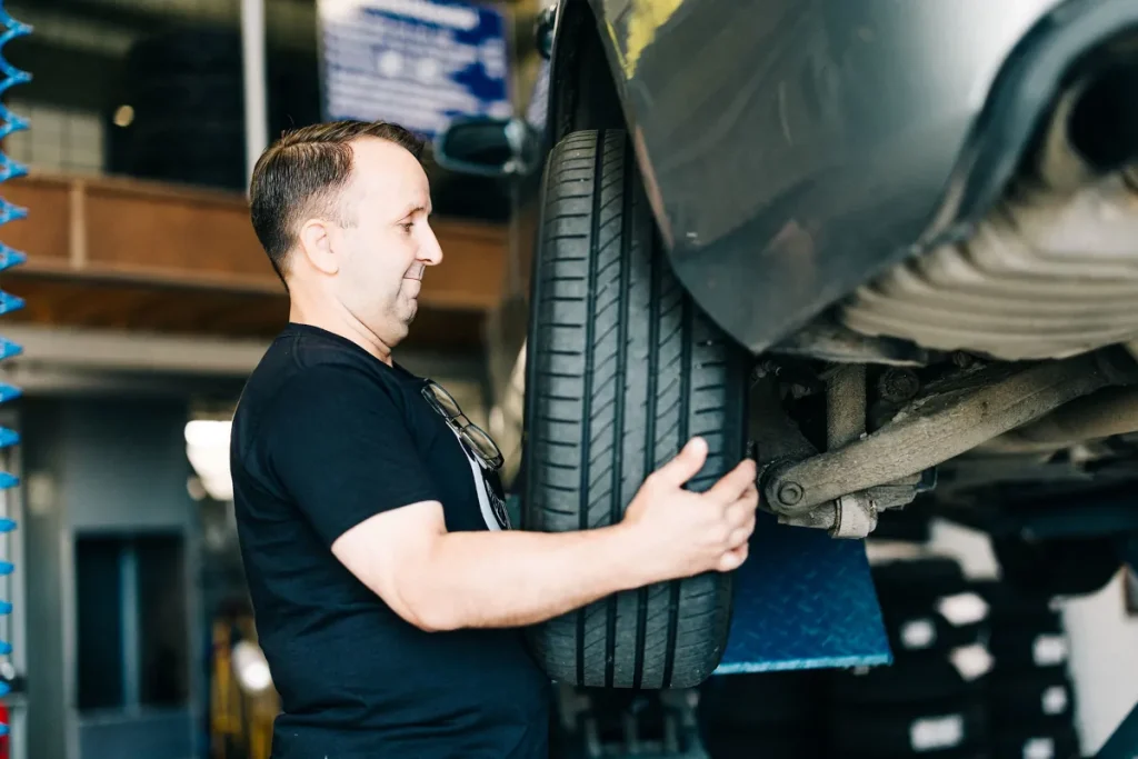 Autotarvikkeen työntekijä asentamassa uutta rengas autoon.