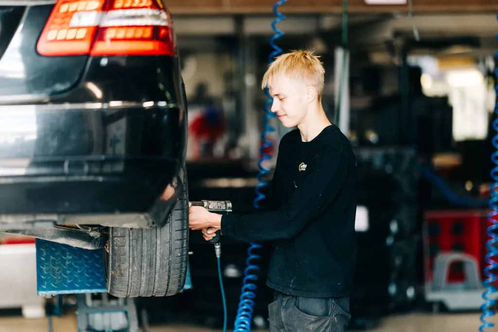 Autotarvikkeen työntekijä kiinnittämässä autoon uutta rengasta.