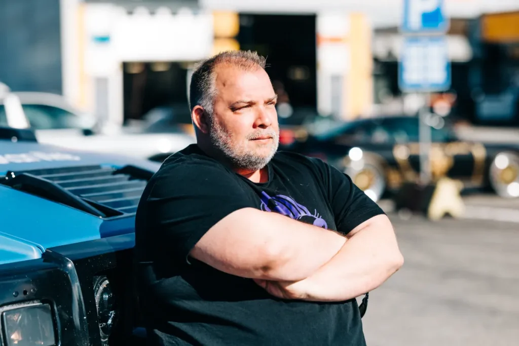 Autotarvikkeen omistaja seisomassa auton vieressä.