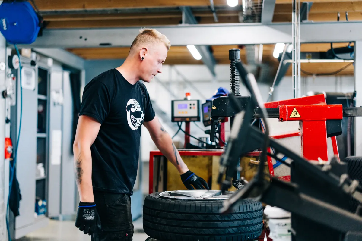 Autotarvikkeen rengasasentaja asentamassa uutta auton rengasta vanteelle.